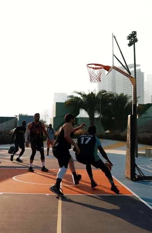 Tall basketball players playing outdoor basketball on court, Player is driving baseline while the defender is trying to steal the ball.