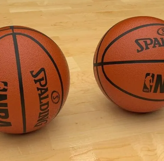 2 basketballs on the ground on court.