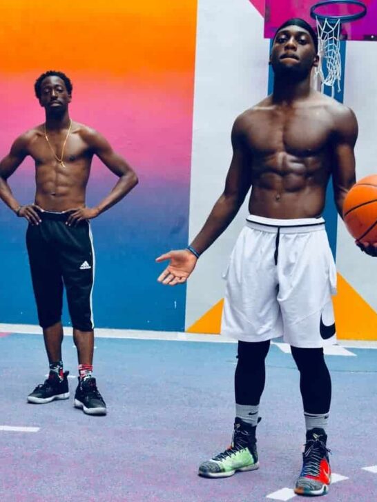 two basketball players posing for the camera on the court.