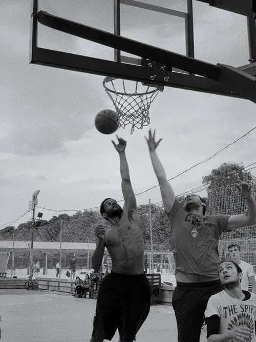 Two tall basketball players jump up for a rebound in black and white photo.
