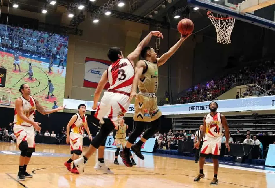 Player laying up the basketball into the basket while getting fouled.