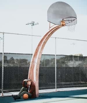 teenager sitting under basketball hoop