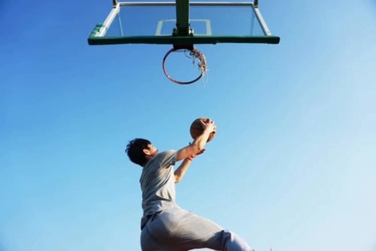 basketball player doing a layup on outdoor up sky showing